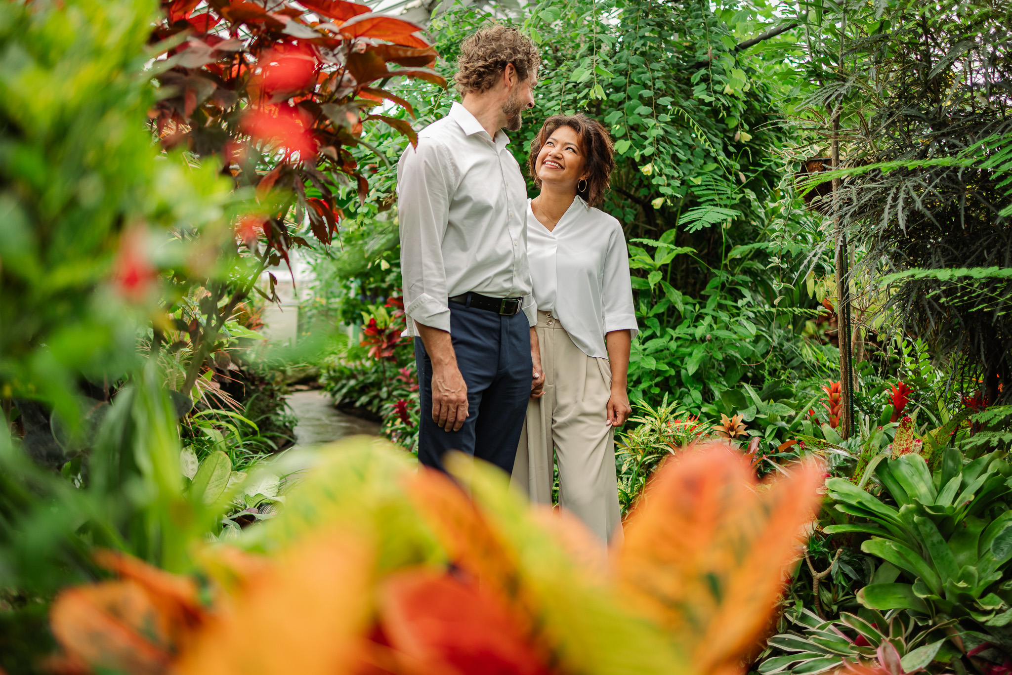 Candid engagement photos at Allan Gardens Toronto featuring couple walking hand in hand through indoor greenhouse garden.