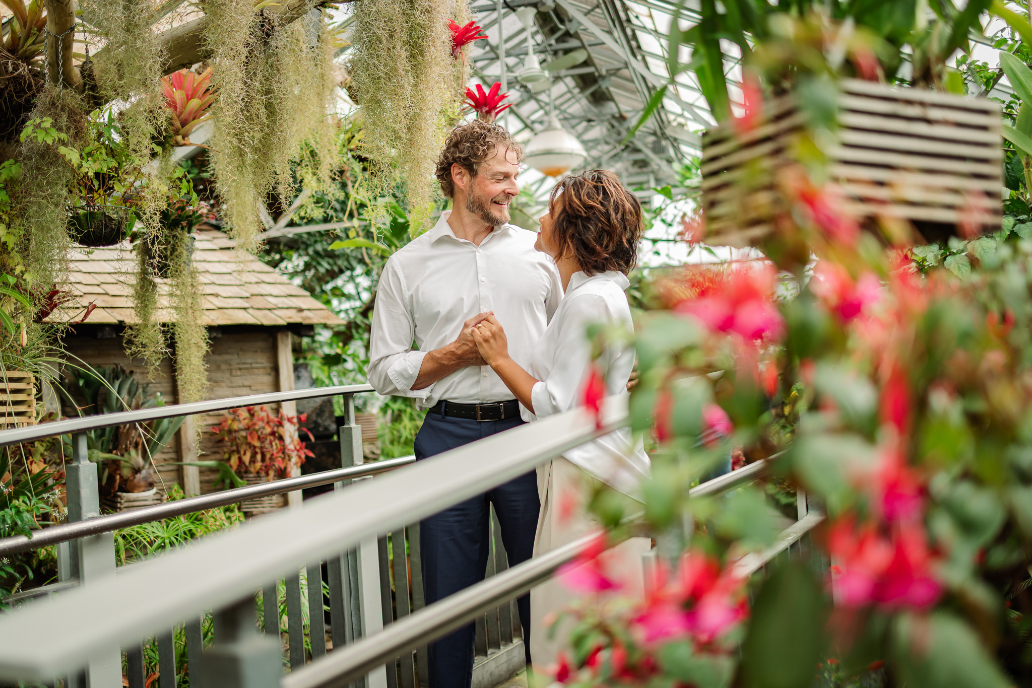 Couple holding hands inside Allan Gardens Conservatory in Toronto during a romantic indoor engagement photo session surrounded by tropical greenery.
