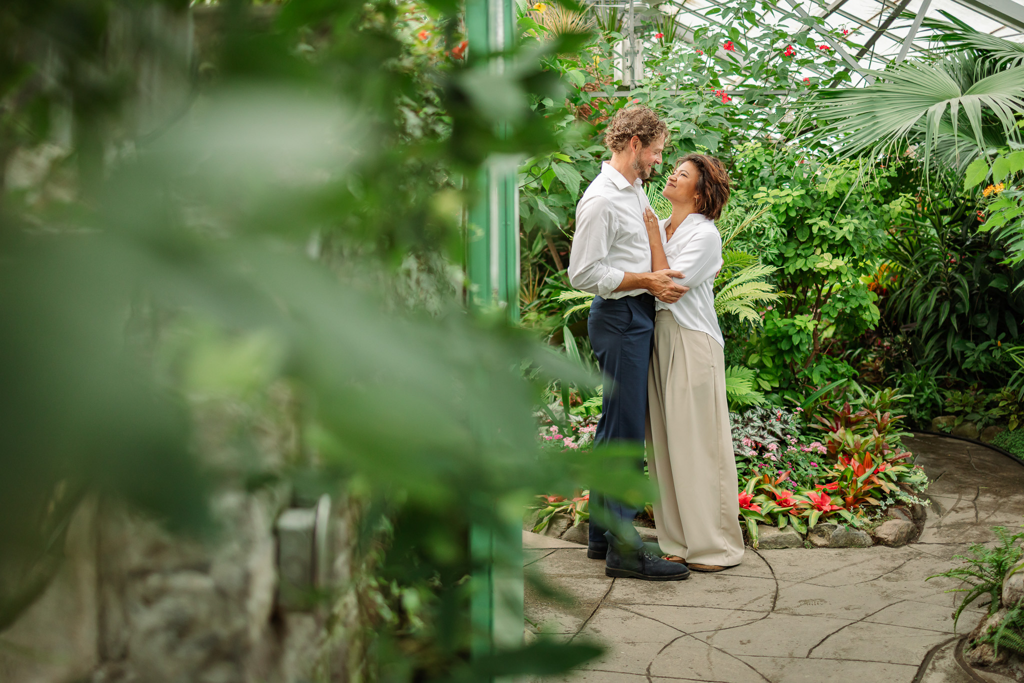 Romantic Allan Gardens engagement photos Toronto with couple standing among lush greenery inside the historic conservatory.